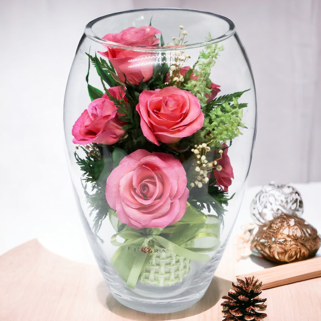 Rosy Charm: Seven Bright Pink Roses in an Elliptical Round Glass Vase