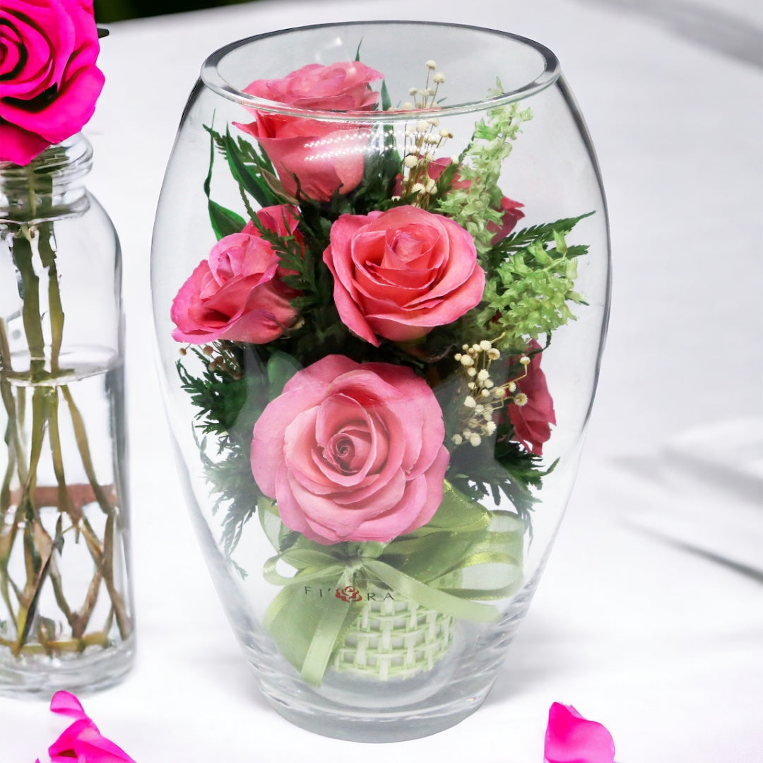Rosy Charm: Seven Bright Pink Roses in an Elliptical Round Glass Vase