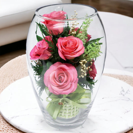 Rosy Charm: Seven Bright Pink Roses in an Elliptical Round Glass Vase