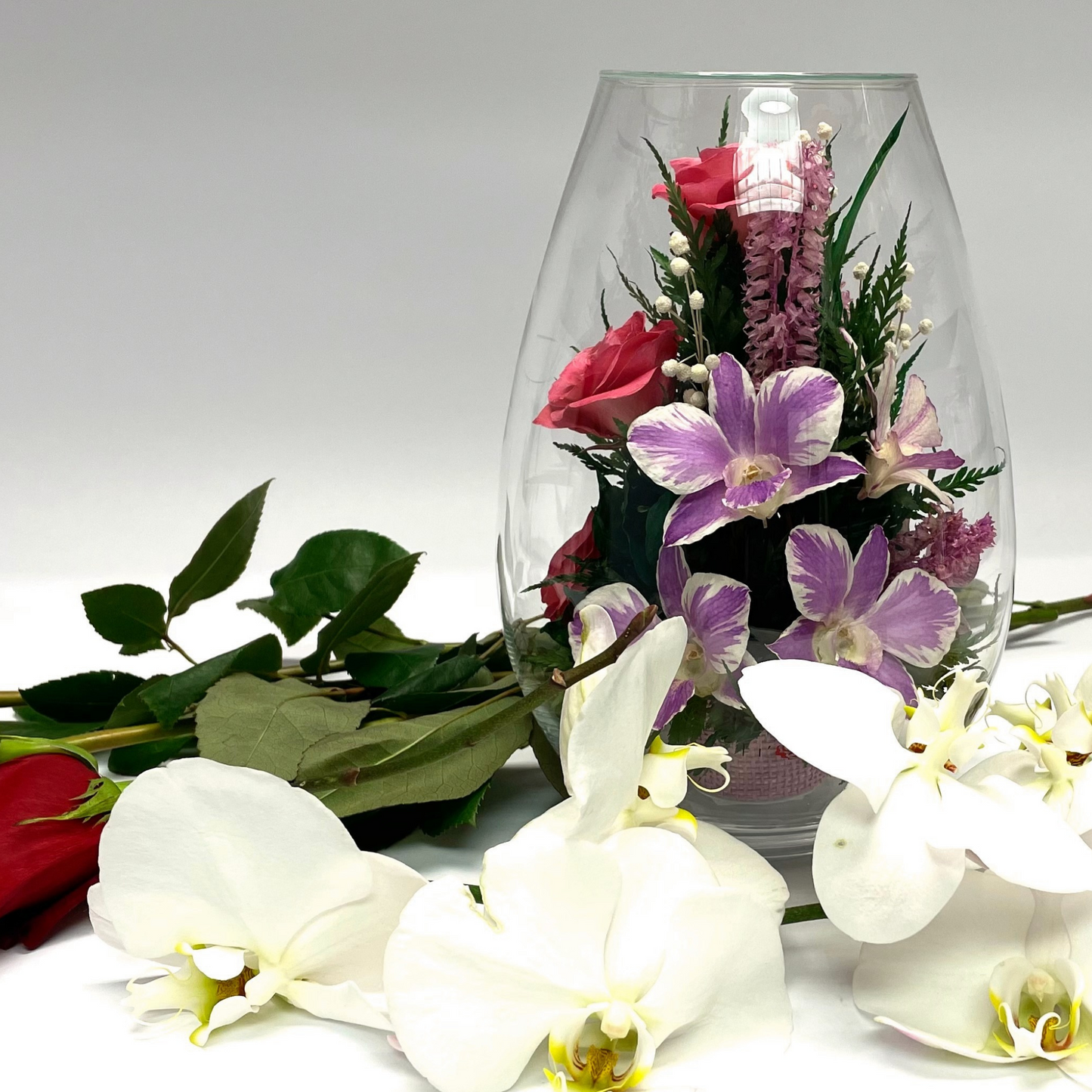 71843 Long-Lasting Pink Roses, Purple-Striped White & King Dragon Orchids in a Droplet Glass Vase